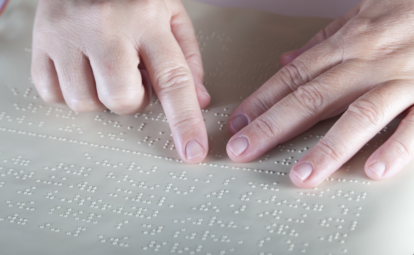 Hands reading an embossed braille document.