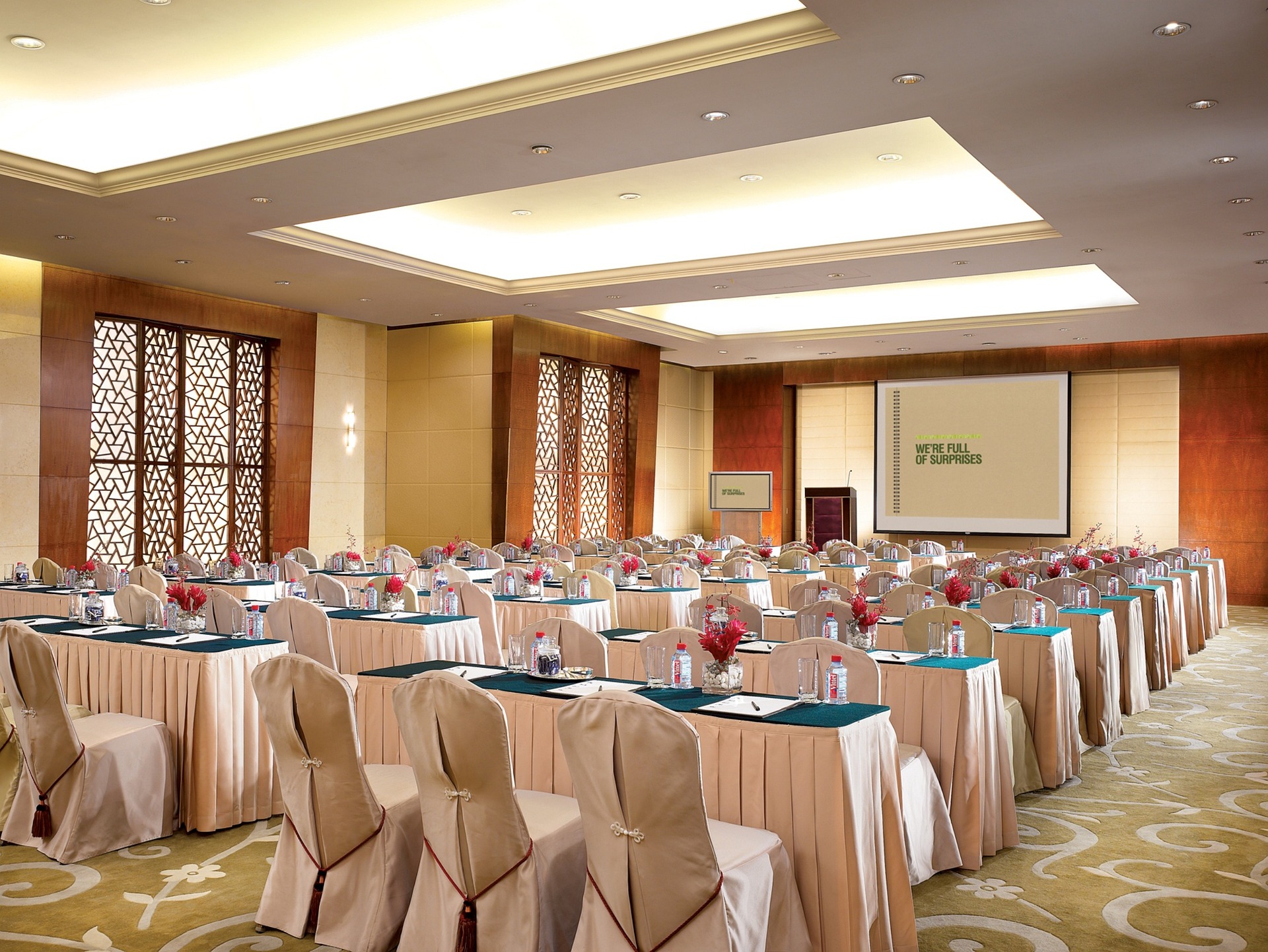 A meeting room with tables and chairs. A projecter is displaying a slide at the front of the room
